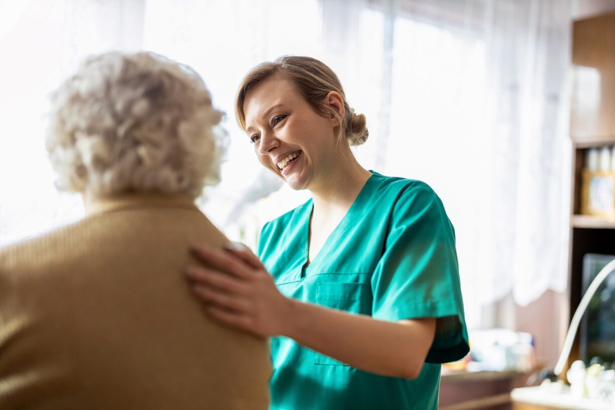 Smiling nurse provides reassuring, compassionate nursing care and support to an elderly resident.