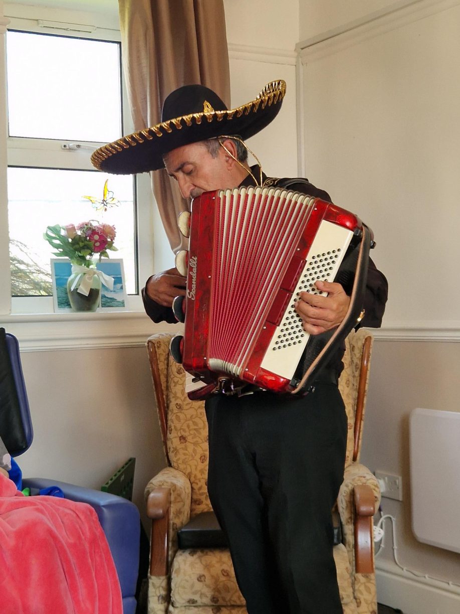 Live music entertainment and performance during the International Tea Day Celebration, featuring a musician with an accordion and a themed hat.