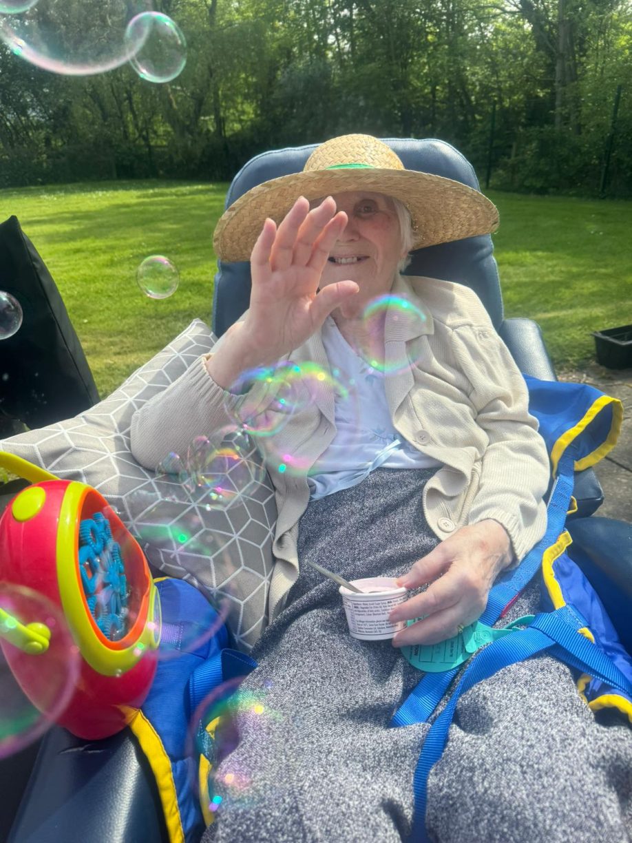 Ann enjoying the sunshine and bubbles at Fairways Newydd care home.