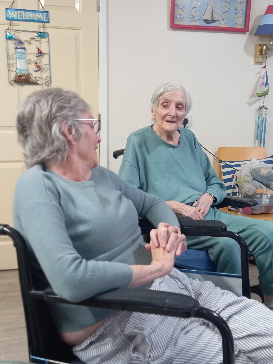 Elderly female residents sitting in their chairs and smiling while having a good chat