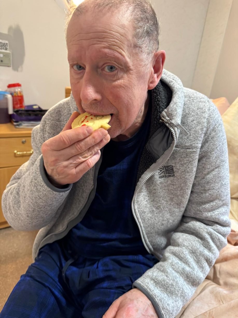 Elderly male resident eating a decorated Halloween cookie.