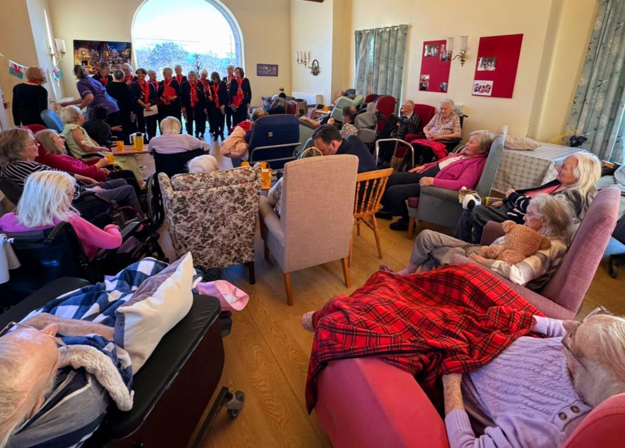 Residents gathered in a lounge to watch a choir perform Christmas carols.